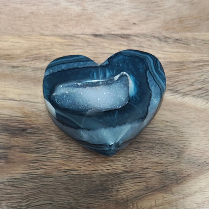 Heart-shaped stone on a wooden surface with a blue background