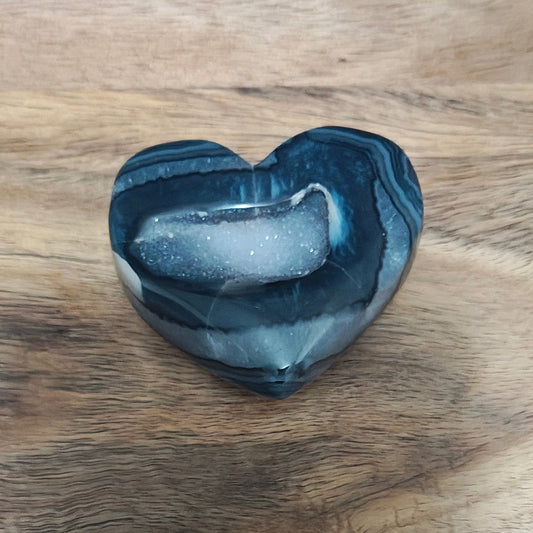 Heart-shaped stone on a wooden surface with a blue background