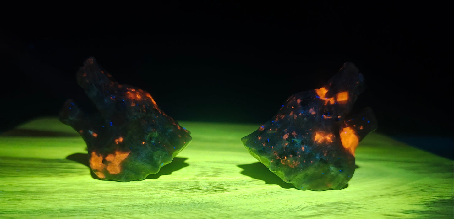 Two glowing rocks on a green surface with a dark background